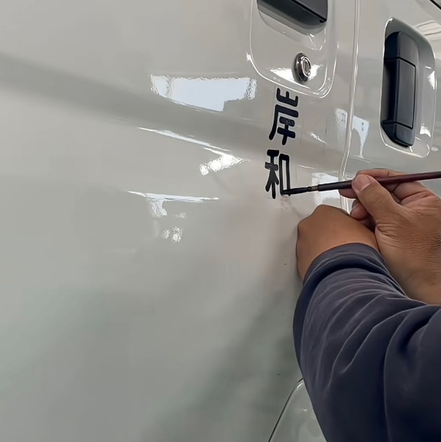 筆で一文字ずつ車体に書き込んでいきます／shu kanbaさん（@signsshu）提供