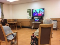 いきいきオンライン寄席を楽しむお年寄り。モニターの前にパソコンを置くことで、双方の声の行き来が可能に（マグナム小林師提供）