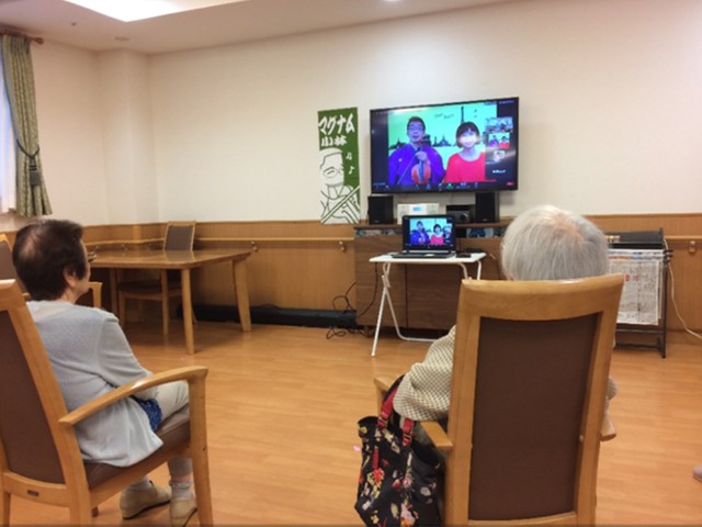 いきいきオンライン寄席を楽しむお年寄り。モニターの前にパソコンを置くことで、双方の声の行き来が可能に（マグナム小林師提供）