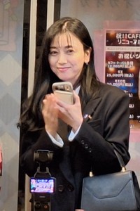 スマートフォンを手に微笑む斉藤りえ氏＝＝東京・浅草の「CＡＦＥオカオカ」