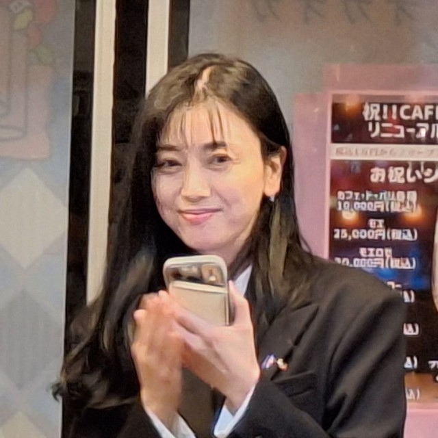 スマートフォンを手に微笑む斉藤りえ氏＝＝東京・浅草の「CＡＦＥオカオカ」