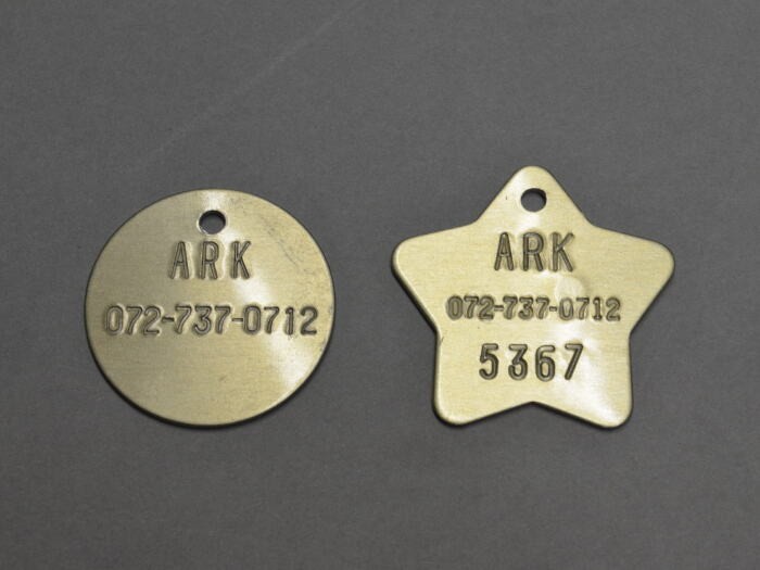 丸いプレートは保護している犬の首輪に、星形は新しい家族の元に送り出した犬の首輪に付ける。星形に刻まれているのは１匹ずつの固有番号とアークの電話番号。万が一、譲渡後に犬の行方が分からなくなった場合、保護した人がこの番号からアークに電話し４桁の番号を伝えれば、どの犬かがすぐに分かる仕組み。