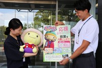 「世界ご当地キャラグランプリ」の投票をお願いするポスターと明智かめまるのぬいぐるみ（亀岡市役所）