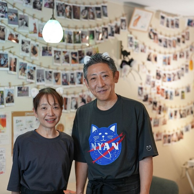 田辺さんご夫婦。いつも頭には猫の耳を付けて接客している。「毎月２２日には、猫好きさんたちが集まる会も開催（不定期）しています」（篤史さん）