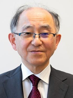 永長直人さんの顔写真。白い背景で、白いシャツに濃いグレーのスーツ、えんじ色のネクタイとメガネを着用