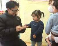 こども園に娘（左から２人目）を預けるアルフィさん（左）＝同町