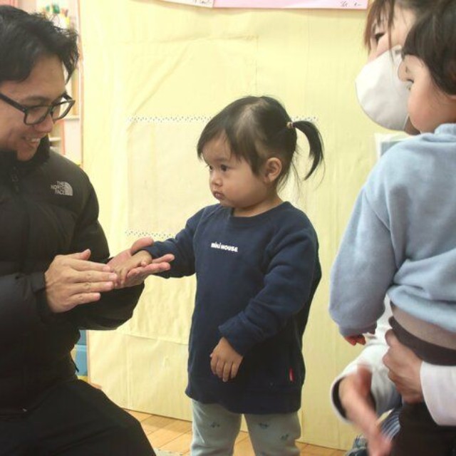 こども園に娘（左から２人目）を預けるアルフィさん（左）＝同町