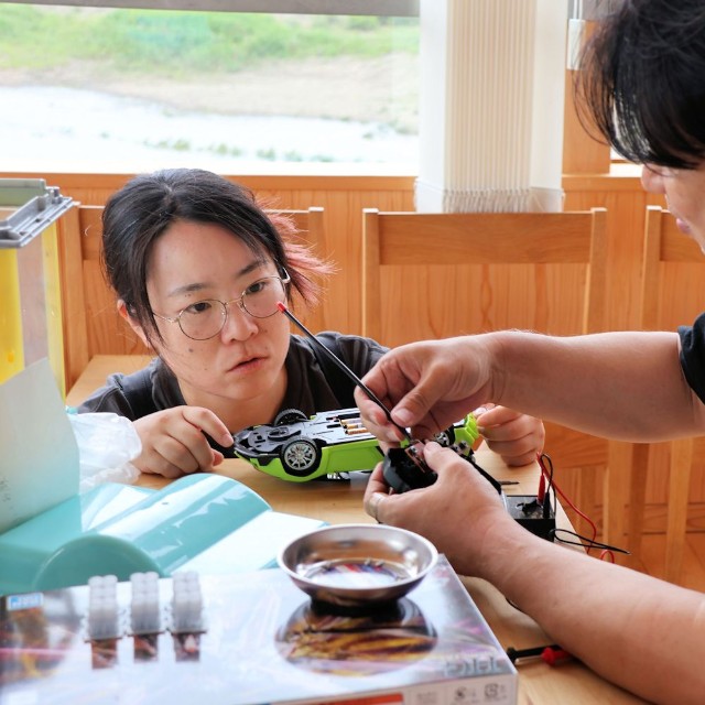 ごみの学校の「リペアカフェ」でラジコンのコントローラーの修理方法を学ぶ参加者（左）