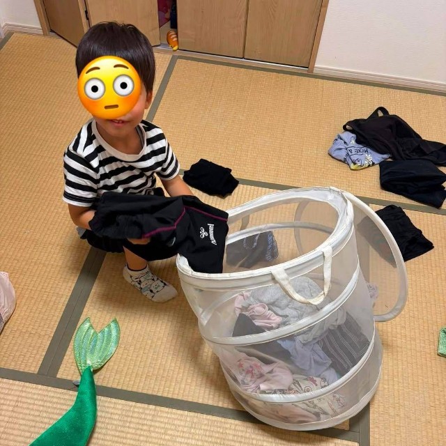洗濯物かごの前で服をたたむ男の子（まゆこさん提供）