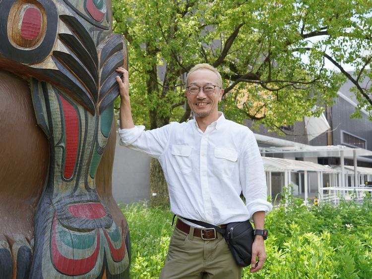 国立民族学博物館のトーテムポールの脇に立つ高野秀行さん