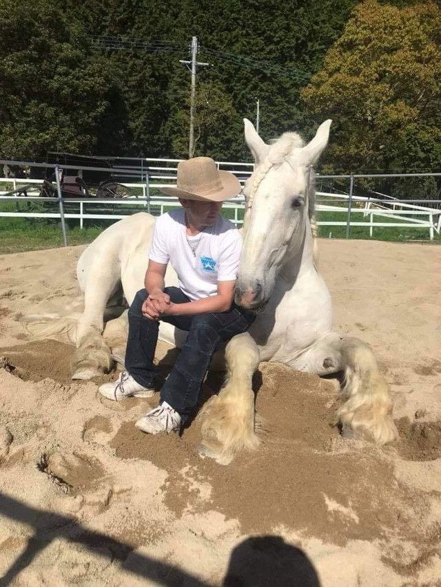 厩舎の砂場で愛馬と戯れる貞松さん