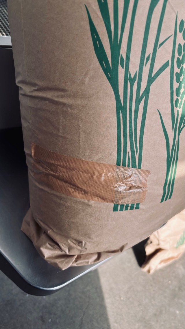 シートベルトの受け口が刺さって破れ、テープで補修された米袋／むちことこつぶさん（@muchi.photo）提供