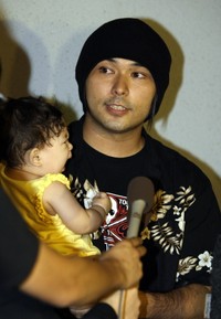 娘を抱いて桑名正博の病状を報告する美勇士＝22012年