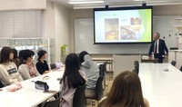 学生らにおせち料理のいわれなどを説明する長嶋社長（右奥）＝宇治市・京都文教短期大、京都府提供
