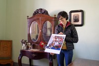 別荘にある化粧棚とアイーダさん。この化粧棚をキュビズムやフォービズムの影響を受けて描いたミロの「馬、パイプ、赤い花」（1919年）が印刷されたスケッチブックを持つマス・ミロ財団のアイーダさん