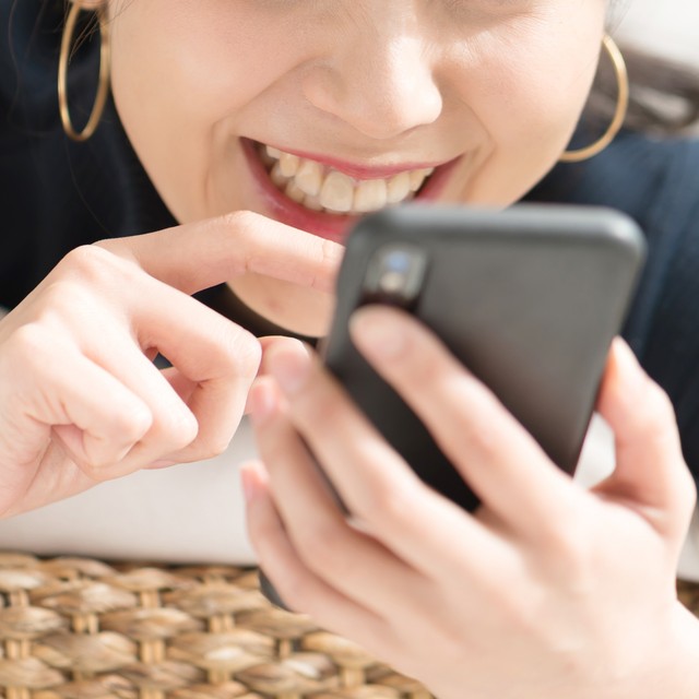 スマホゲームをする女性※画像はイメージです（naka/stock.adobe.com）