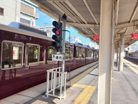 晴れの日の正雀駅ホーム。光や周囲の映り込みが反射し輝く阪急電車