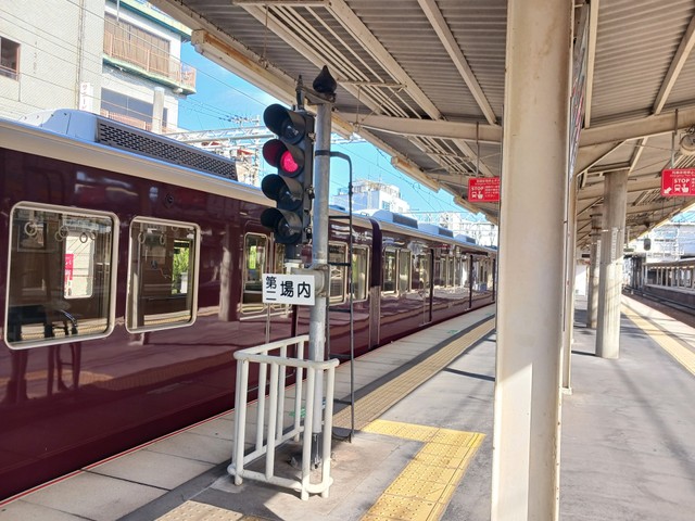 晴れの日の正雀駅ホーム。光や周囲の映り込みが反射し輝く阪急電車