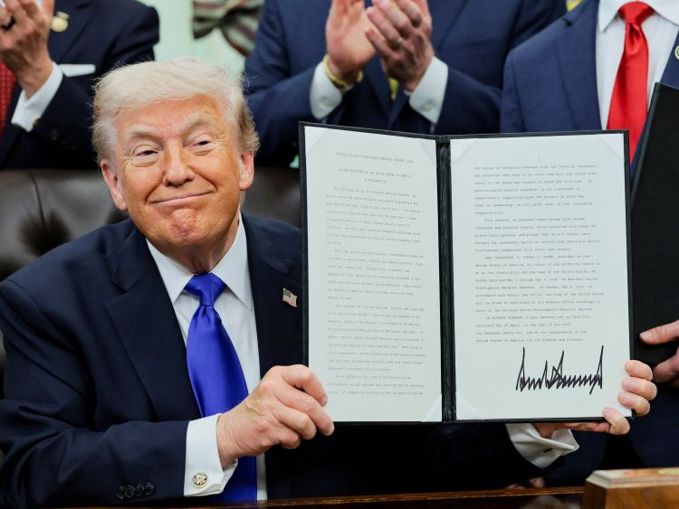 米ホワイトハウスで2026年4月30日、署名した退職金制度に関する大統領令を笑顔で披露するトランプ大統領＝ロイター