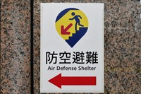 台北駅の出入り口に貼られた、防空壕を示す新たなデザインの標識。駅の地下街が壕を兼ねている＝台北市、石田耕一郎撮影