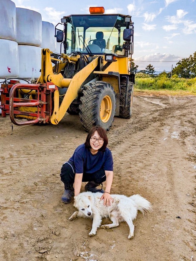 よしださんと愛犬と作業機械とラップされた牧草（提供：よしださん）