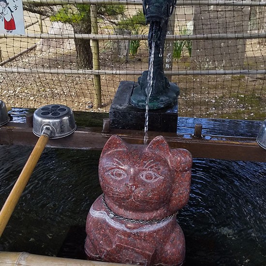 福良天満宮の入り口にある手水舎には、赤御影石の招き猫が