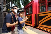 駅長の帽子をかぶって、嵯峨野トロッコ列車に手を振る野々村忠壮ちゃん（京都市右京区・トロッコ嵯峨駅）