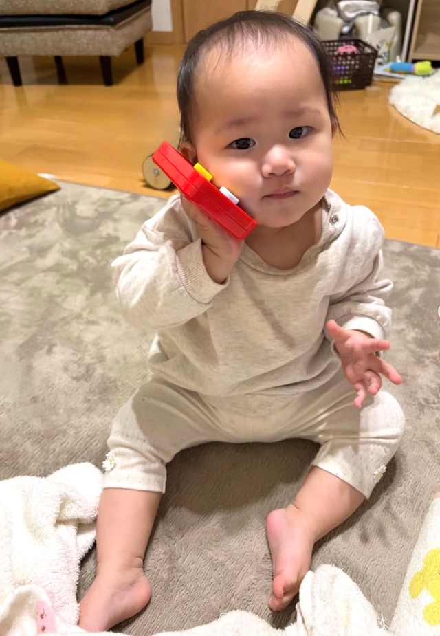 スマホでパパに「もしもしー？」生後11カ月のRANちゃん（提供：@uchinomanmaruranchanさん）
