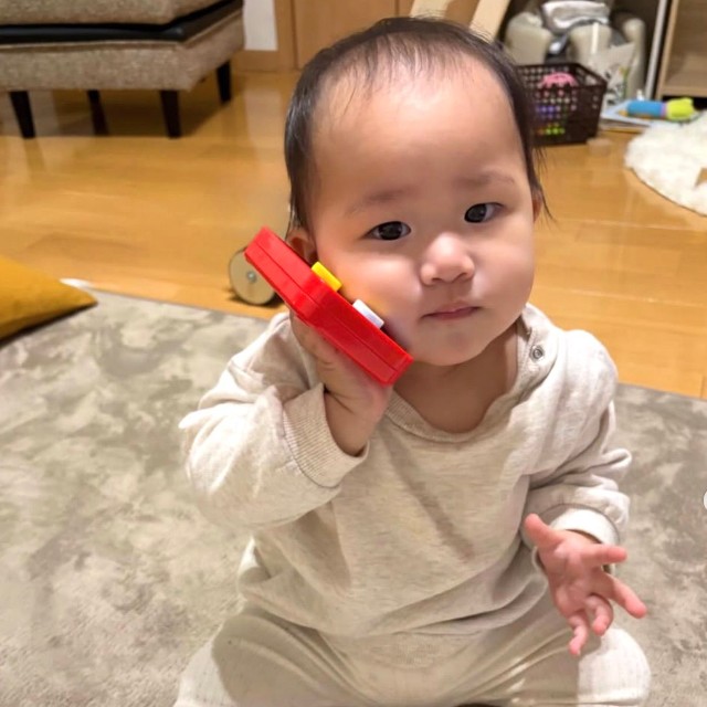 スマホでパパに「もしもしー？」生後11カ月のRANちゃん（提供：@uchinomanmaruranchanさん）

