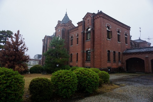 旧奈良監獄の事務棟。低く重い雨空を背景にレンガ造りの建物がくっきりと浮かび上がる