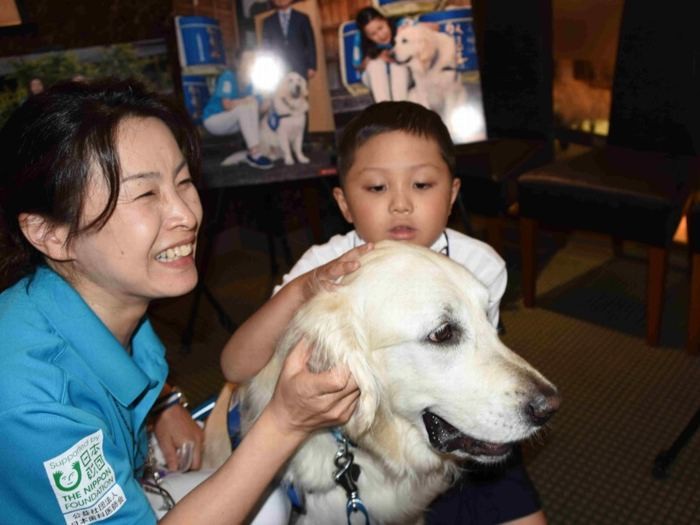 静岡県立こども病院のファシリティードッグ「ヨギ」の誕生会。ハンドラーの鈴木さん（左）