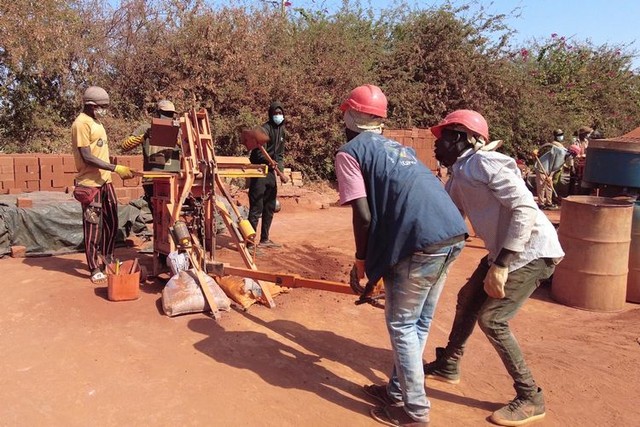 人力の圧縮機械を使い、土れんがをつくる「エレメンテール」の作業員ら＝2023年12月23日、セネガル西部、荒ちひろ撮影