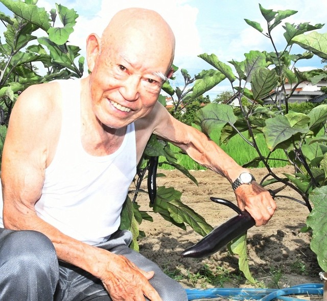 細い実が分かれた珍しい形のナスを手にする佐藤豊さん＝島根県出雲市斐川町