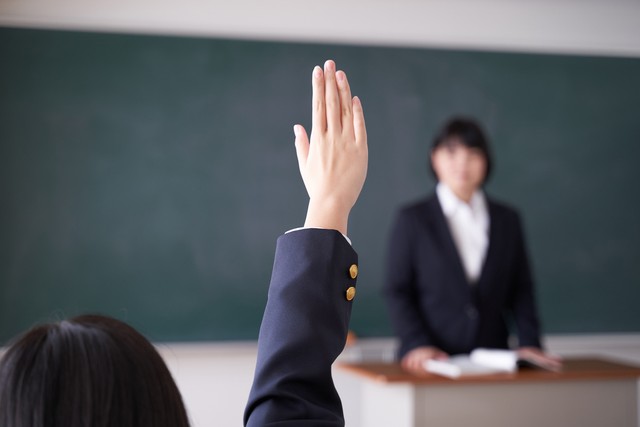 手をあげる学生※画像はイメージです（mapo/stock.adobe.com）