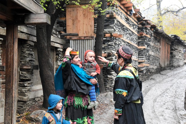 カラーシャの谷の住民と談笑する和田晶子さん（右）。女性たちは普段から色鮮やかな伝統衣装を着ている＝2019年4月17日、パキスタン北西部、乗京真知撮影