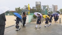 小雨が降る中、児童が元気に登校