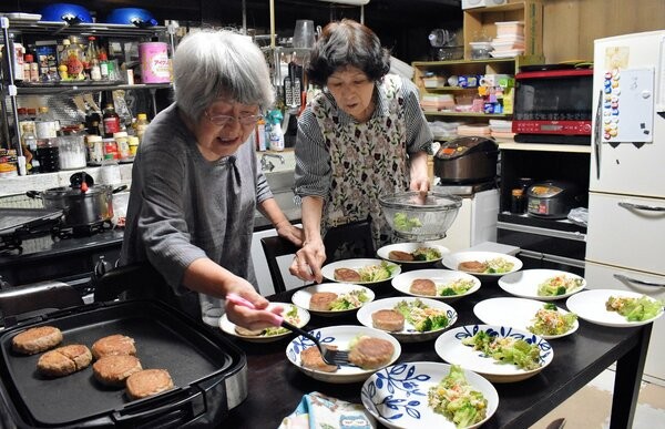 ひとり親家庭の子どもたちのために、ハンバーグやサラダなどの夕食を盛り付ける木津川母子会の小玉さんたち（木津川市木津）