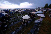 昨年の花火大会直前、降り出した大粒の雨に傘をさすなどする人たち（２０２５年８月８日午後６時４１分、大津市島の関）