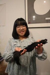 カットした髪を手に笑顔を見せる池田さん