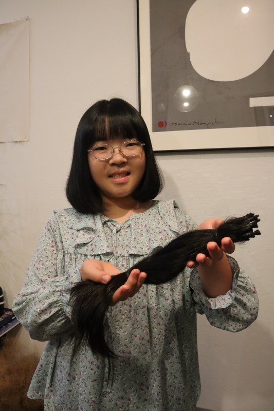 カットした髪を手に笑顔を見せる池田さん