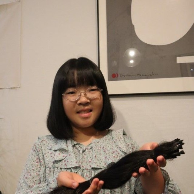 カットした髪を手に笑顔を見せる池田さん