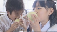岡山県産の白桃にかぶりつく児童