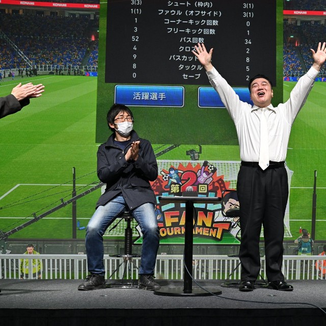リアルイベント「ウイコレ FAN TOURNAMENT」で連覇を達成し、両手を挙げて喜ぶ山崎弘也（中央）