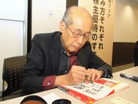 講演会で著書にサインする桐谷広人さん＝神戸市内