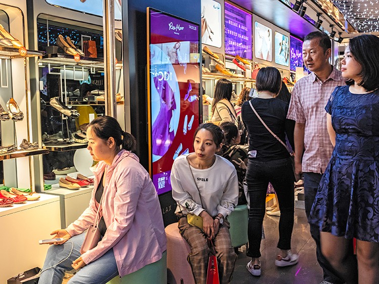 Shoppers look at shoes in a Beijing mall, May 18, 2019. Chinese consumers, who have become more cautious over the past year, are now staging a broad retreat. They are buying fewer cars, smartphones and appliances, going to the movies less and taking fewer trips abroad. (Lam Yik Fei/The New York Times)