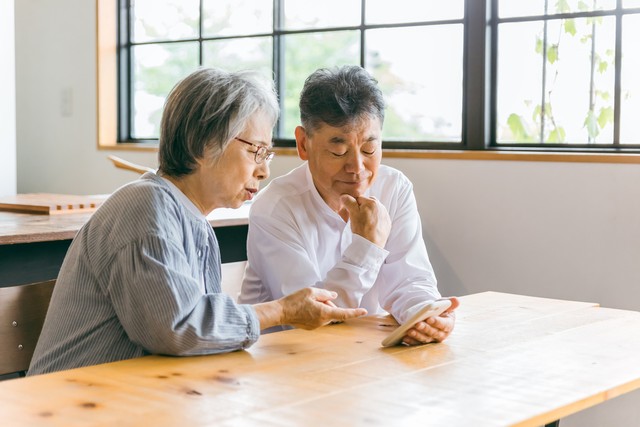 スマホを見て悩む夫婦※画像はイメージです（buritora/stock.adobe.com）