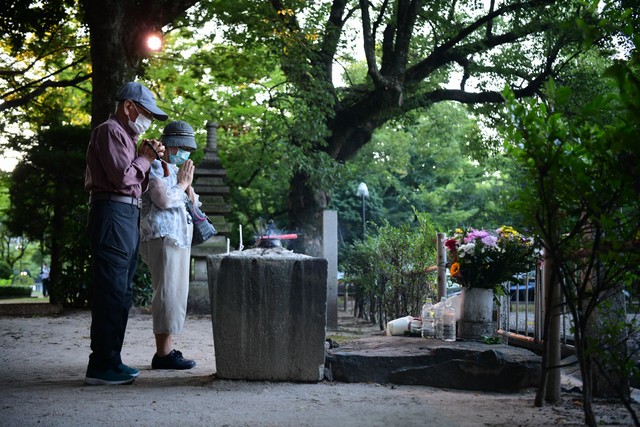 原爆投下から76年を迎えた朝、原爆供養塔に手を合わせる人たち＝2021年8月6日午前5時59分、広島市中区、金居達朗撮影