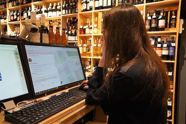 政府のシェルター地図を調べる酒屋の店員。地図によると、この建物にはシェルターがあるはずだが･･････＝2023年6月3日、ワルシャワ中心部、荒ちひろ撮影