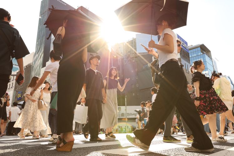 強い日差しの下、東京・銀座の歩行者天国を歩く人たち
