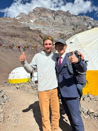 アコンカグアを登頂成功し、ガイドと肩を組む佐田展隆氏（本人提供）